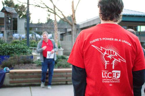 union member wearing LCCEF shirt and listening to rally speaker